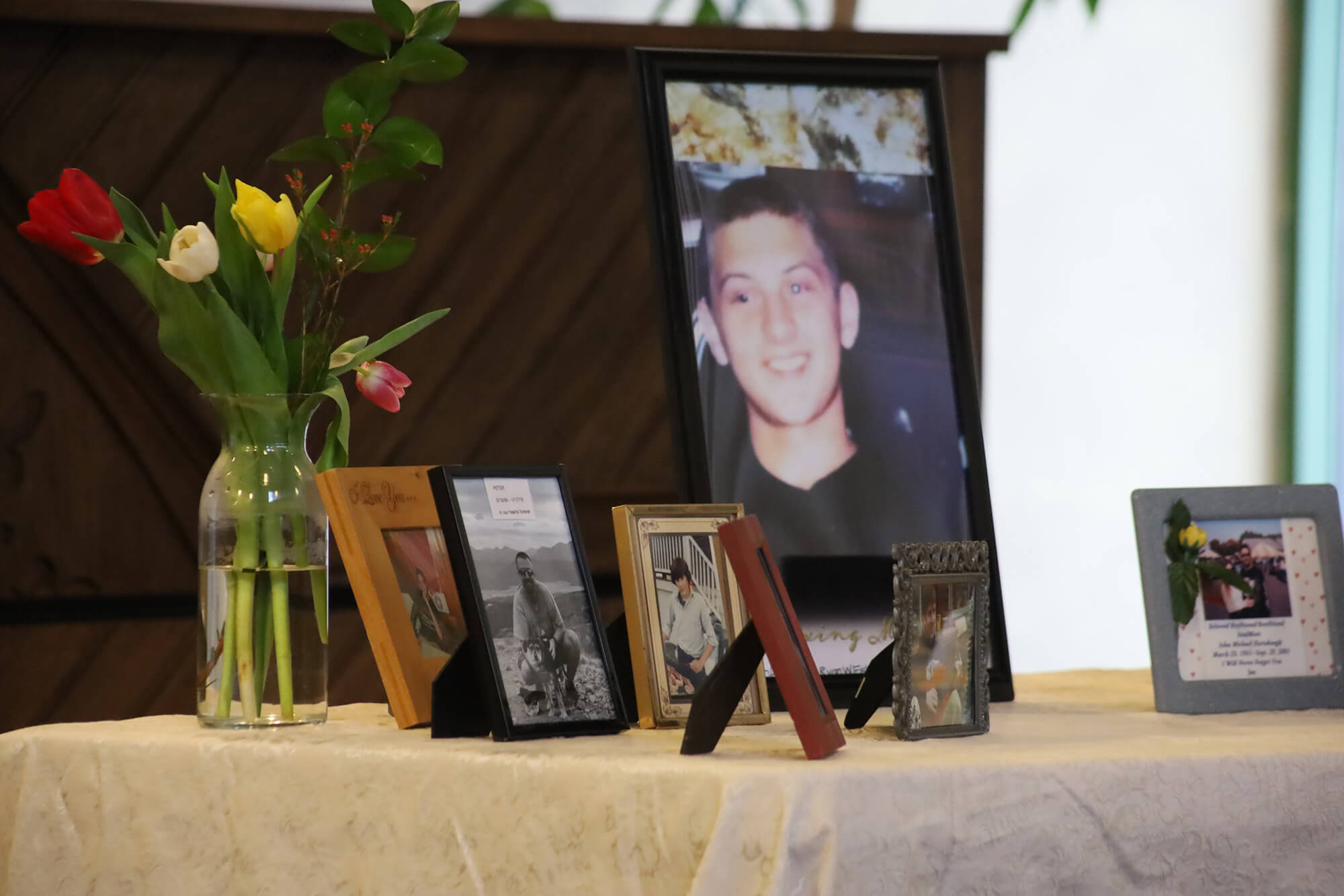 A memorial table with framed photos and a vase of flowers.