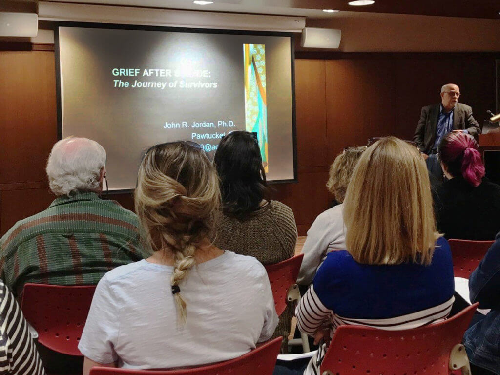 group of people indoors looking at a presentation on grief after suicide