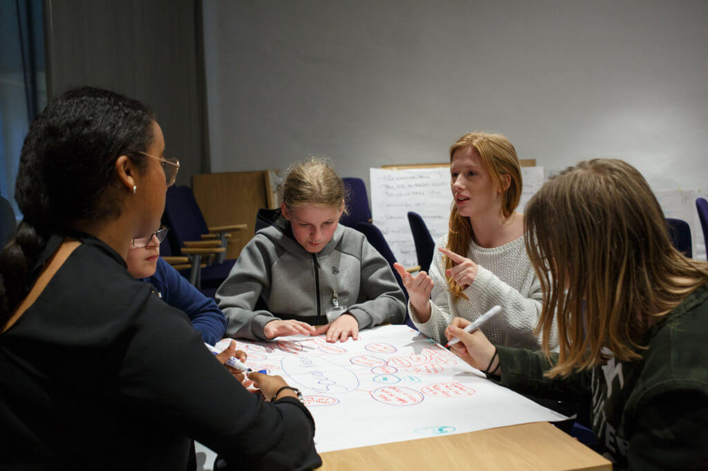 A group of children working on a chart while sitting around a table.