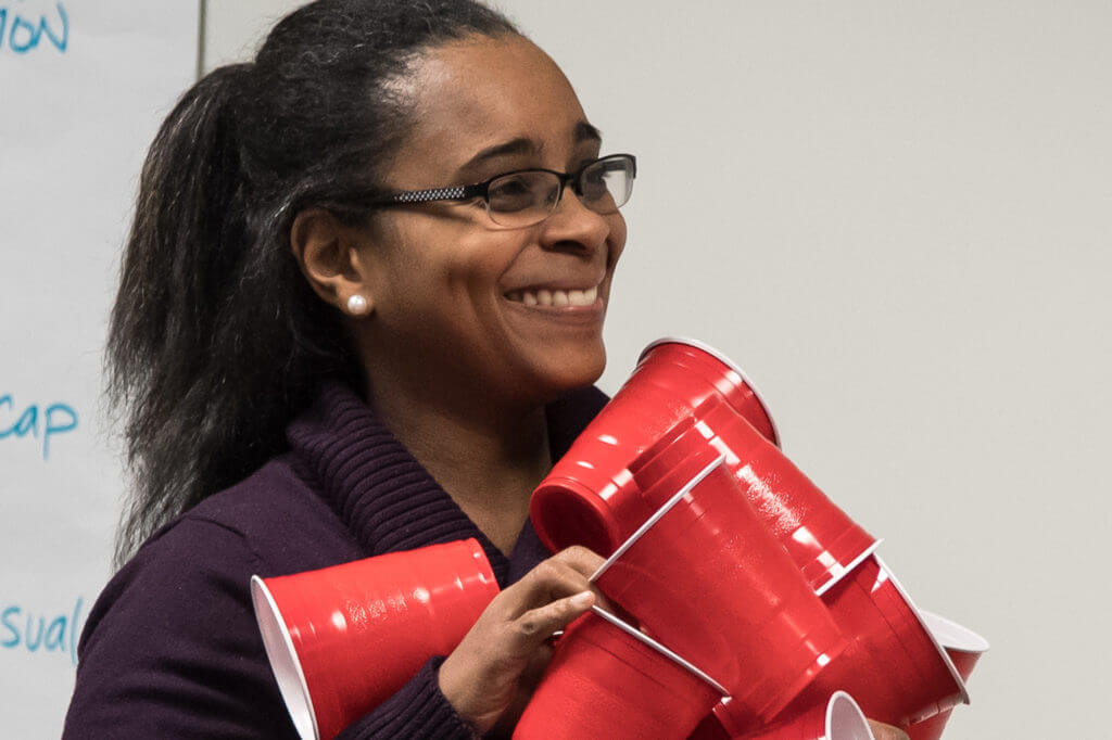 A woman holding a stack of red solo cups.
