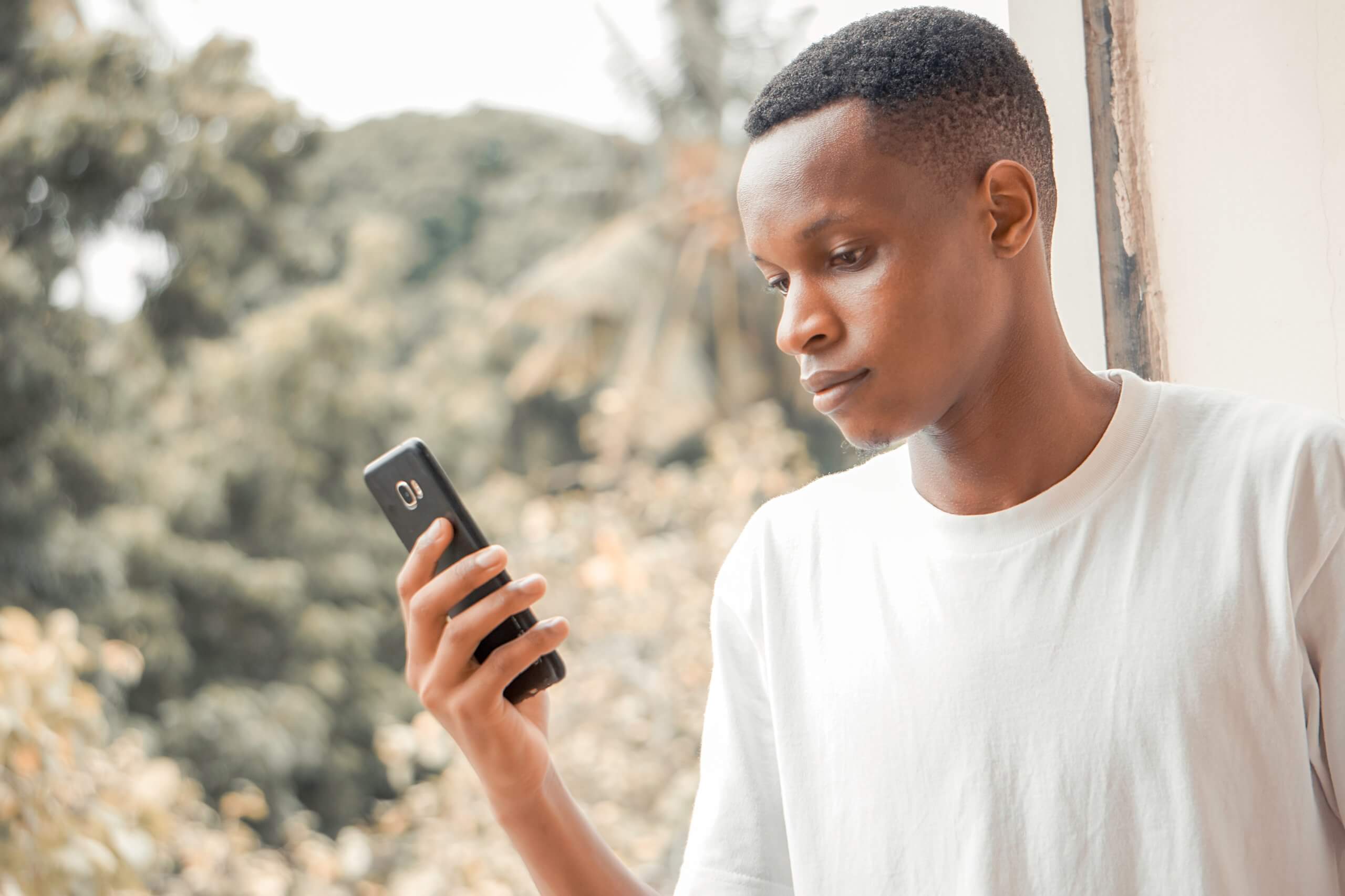 person looking at phone next to large window