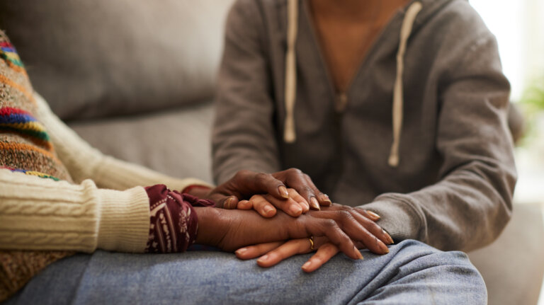 Two people offering comfort while holding hands