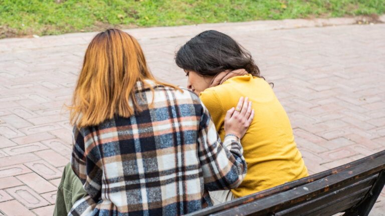 young woman consoling her friend on the public park
