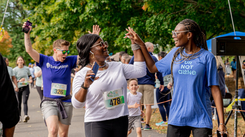 Two women high fiving at the 26th Annual Samaritans 5k.