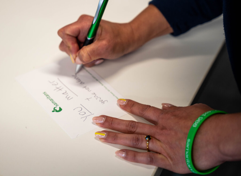 A volunteer from Deloitte writes a note to include in a Basic Needs kit.