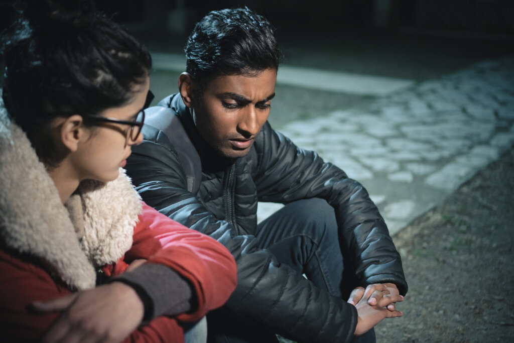 A woman sitting on a sidewalk and talking to her suicidal friend