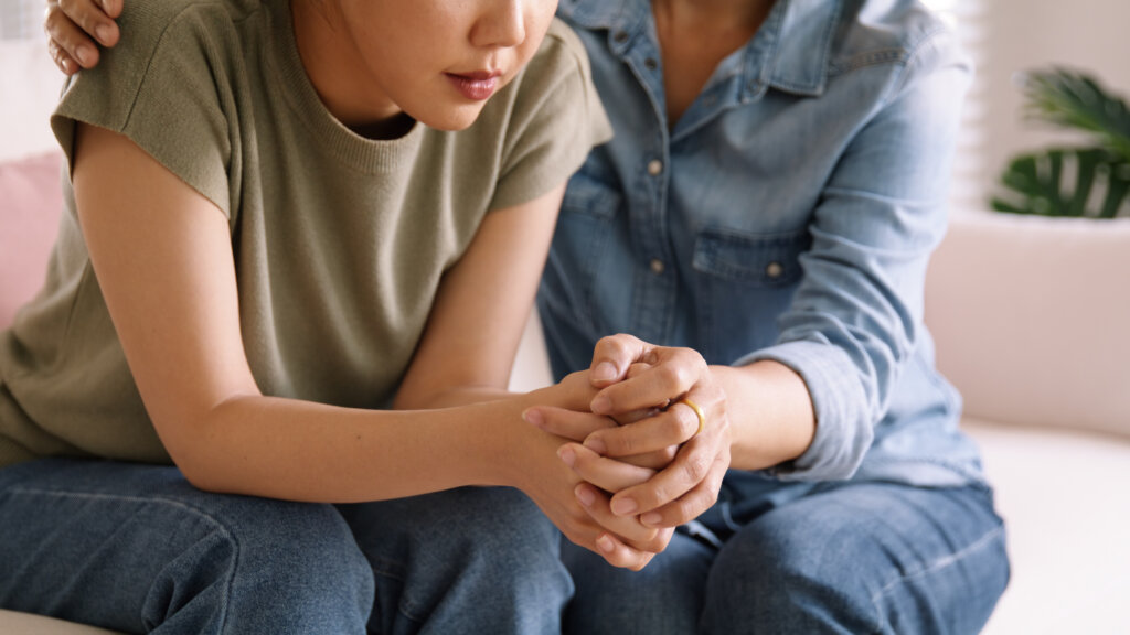 A woman sitting and comforting another woman on a couch