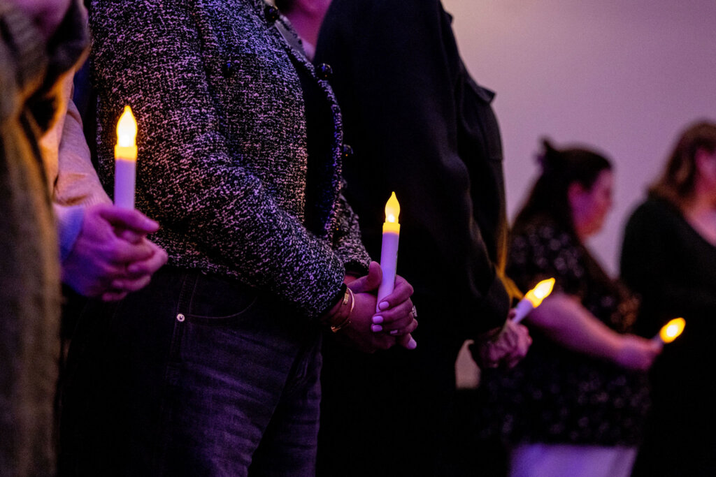 Participants standing and holding candles during a ceremony
