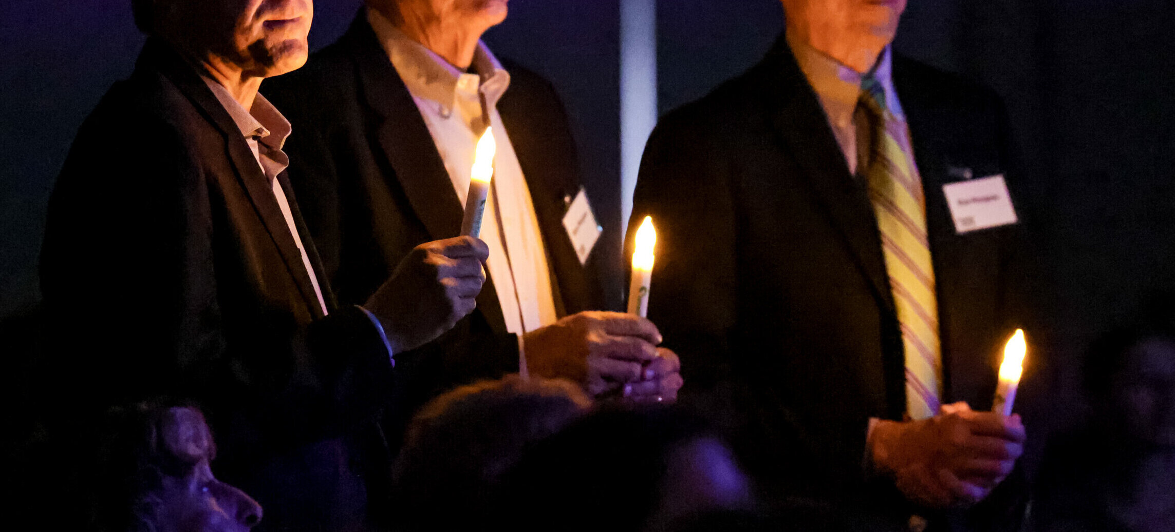 Three individuals holding candles