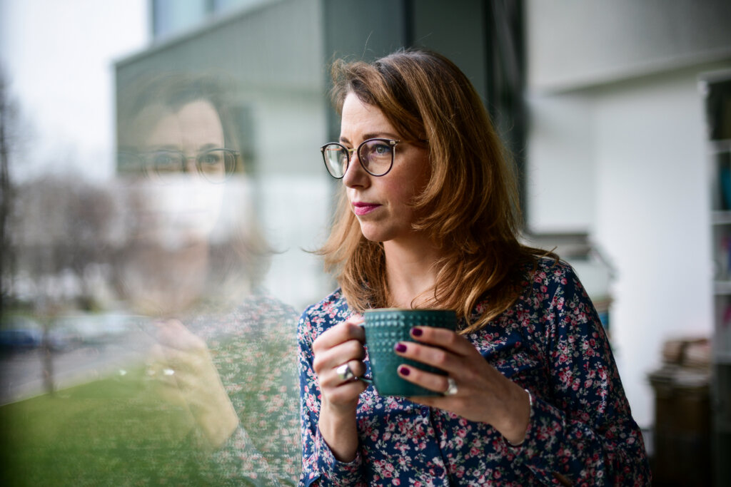 A teacher holding her coffee and looking out the window
