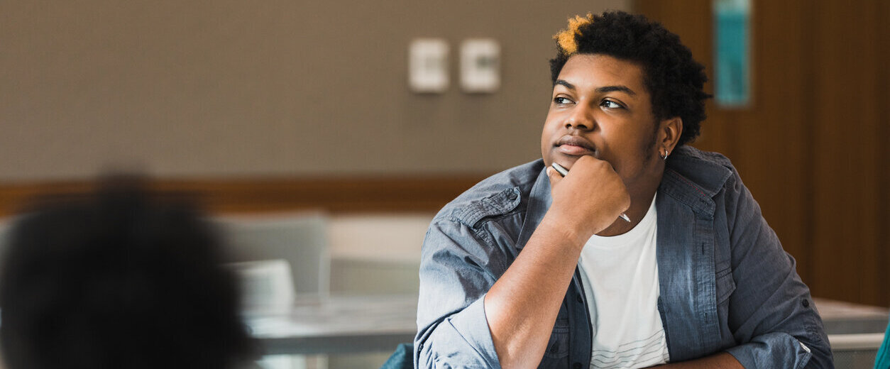 A suicidal student sitting at a desk staring into space and not paying attention in class