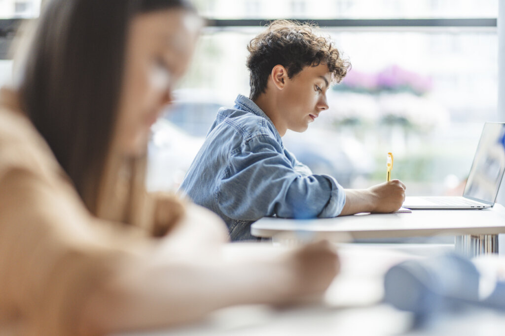 A student struggling with suicidal thoughts writing at his desk