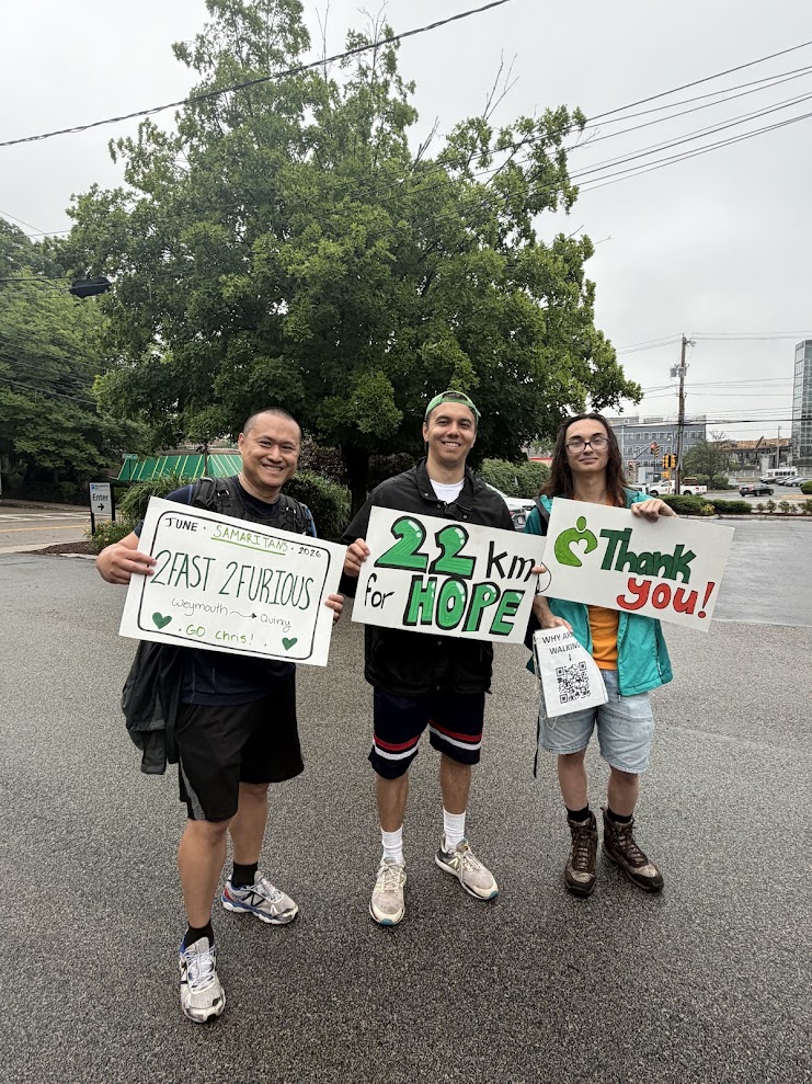 3 men standing holding Samaritans signs after walking 22km for suicide prevention. 
