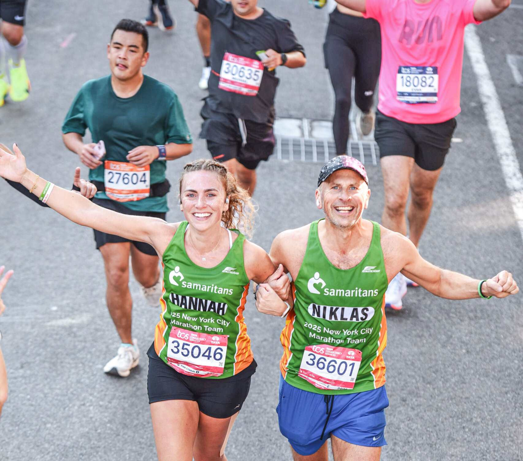 Two runners cross the finish line at the 2025 TCS New York City Marathon.